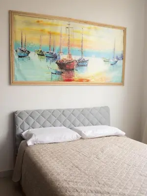 a painting above a bed in a bedroom at SUNSET LATITUDE, Apto frente al mar con hamaca y piscina in Puerto Colombia