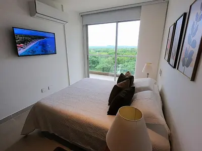 a bedroom with a bed and a large window at Baia Kristal Kabo Apartamento in Cartagena de Indias