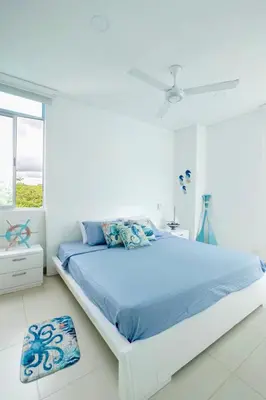 a white bedroom with a bed and a window at Amari Ocean House in Coveñas
