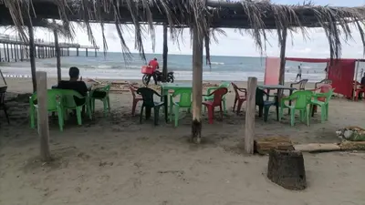 a group of people sitting at tables on the beach at Playas el paraiso in San Bernardo del Viento