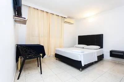 a bedroom with a bed and a chair in it at Hotel Costa Caribe BAQ in Barranquilla