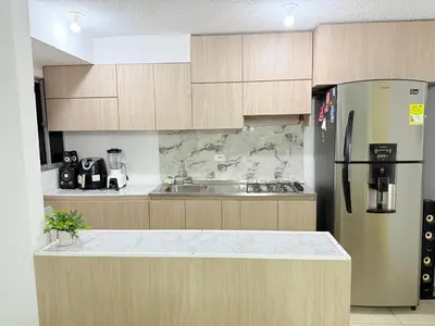 a kitchen with wooden cabinets and a stainless steel refrigerator at Habitación 1 persona cerca de aeropuerto,terminal de buses y estadio in Soledad