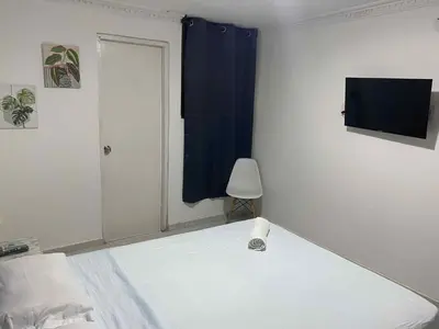 a bedroom with a white bed and a blue curtain at Habitación cerca al aeropuerto # 4 in Cartagena de Indias
