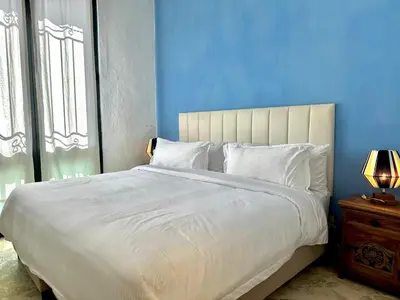 a bedroom with a large white bed with a blue wall at Calamari Homes - El Porvenir 305 - Walled city in Cartagena de Indias