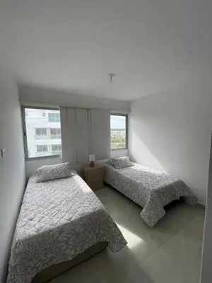 two beds in a room with two windows at An apartment in Serena del Mar in Serena del Mar