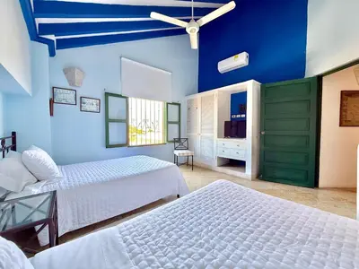 a bedroom with two beds and a blue wall at by Calamari Homes - El Porvenir 402 walled city in Cartagena de Indias