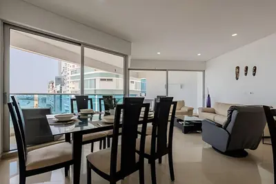 a dining room with a table and chairs and a couch at Espectacular vista al mar - Edificio Infinito 1002 in Cartagena de Indias