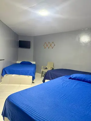 a bedroom with two beds with blue sheets and a tv at Hotel las nubes Barranquilla in Barranquilla
