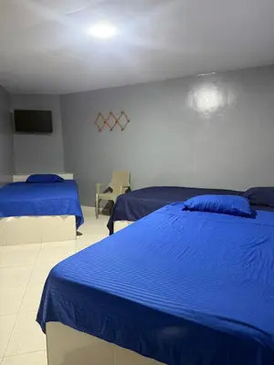 a bedroom with two blue beds and a tv at Hotel las nubes Barranquilla in Barranquilla