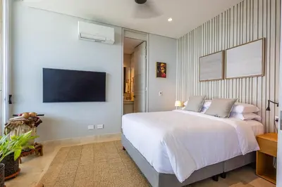 a bedroom with a white bed and a flat screen tv at 4BR Seaview Apartment at Calablanca D5 in Cartagena de Indias