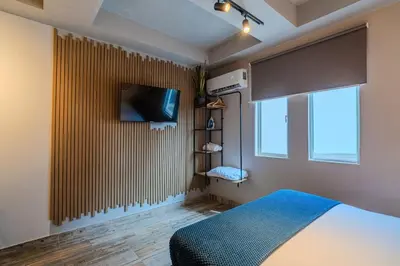 a bedroom with a bed and a tv and a window at Almería Apt, Spacious Studio Near Old Town in Cartagena de Indias