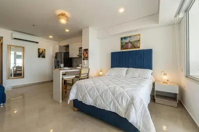 a bedroom with a bed and a desk and a kitchen at CB Lujoso Apartasuit -Vista al mar-linda piscina-cerca al Aeropuerto in Cartagena de Indias