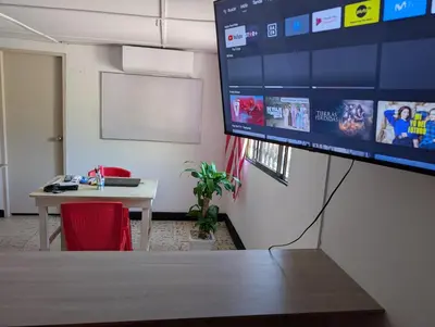 an office with a desk and a large monitor on a wall at English power Exotic point in Barranquilla