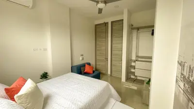 a bedroom with a white bed and a blue chair at Magico Apartamento Frente al Mar 3 Habitaciones BM91 in Coveñitas