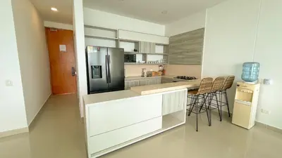 a kitchen with a refrigerator and a counter with chairs at Magico Apartamento Frente al Mar 3 Habitaciones BM91 in Coveñitas
