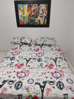 a bed with a comforter with pink flowers on it at hotel restaurante doña nerta in Cartagena de Indias
