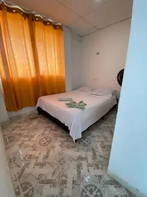a bedroom with a white bed with an orange curtain at Hotel donde Tito in Tolú