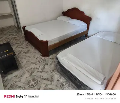 two twin beds in a room with avisor at Hotel donde Tito in Tolú