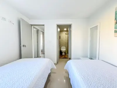 two beds in a white room with a toilet at Azul Caribe 104 in Coveñas