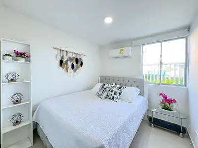 a white bedroom with a bed and a window at Azul Caribe 104 in Coveñas