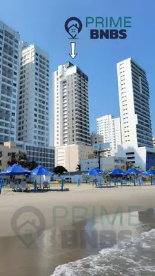 a beach with chairs and blue umbrellas and buildings at Beach Front - Luxury High Rise - Dubai Style in Cartagena de Indias