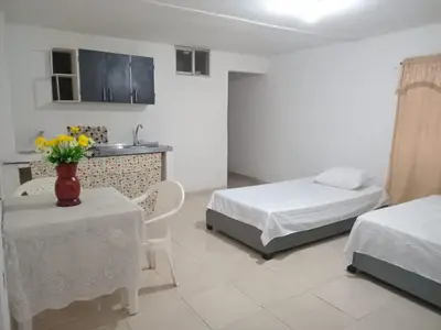a bedroom with two beds and a table and a kitchen at Apartaestudio Barranquilla Calle 87 in Barranquilla