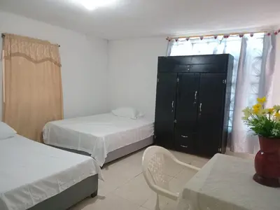 a bedroom with two beds and a cabinet and a table at Apartaestudio Barranquilla Calle 87 in Barranquilla