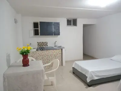 a bedroom with a bed and a table and a kitchen at Apartaestudio Barranquilla Calle 87 in Barranquilla