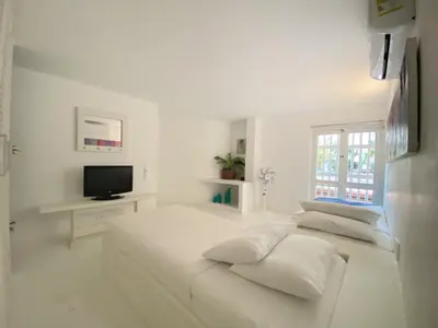 a white bedroom with a bed and a television at Apartment in the Historical Center of Cartagena in Cartagena de Indias