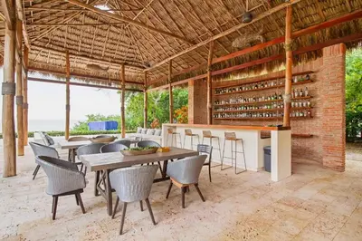 a dining room with tables and chairs and a brick wall at Casa BaruGrande in Cartagena de Indias