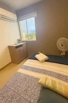 a bedroom with two beds and a dresser and a window at Cartagena Royal Residences 903 in Cartagena de Indias