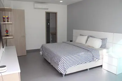 a white bedroom with a bed with striped sheets and pillows at Espectacular apartamento morros 3 in Cartagena de Indias