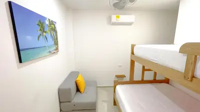 a small room with a bunk bed and a bed and a couch at Habitacion Manglares 101 in Coveñas