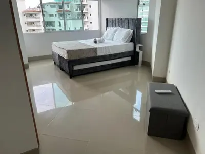 a bedroom with a bed and a bench in it at Apartamento con vista al mar en Bello Horizonte, Santa Marta in Santa Marta