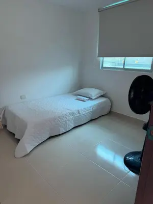 a bedroom with a bed and a window and a chair at Apartamento moderno en zona norte exclusiva in Barranquilla
