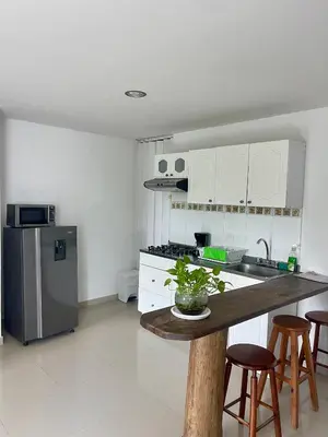 a kitchen with white cabinets and a table with stools at Apartamento 201 frente a hotel Las américas in Cartagena de Indias