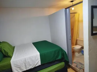 a bedroom with a green and white bed and a bathroom at Hb-m8 House With 8 Bedrooms, Pool And Near The Sea in Cartagena de Indias