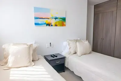 two beds with white pillows and a night stand in a room at Hermoso Apto 2 Hab Piso 11 en Morros City in Cartagena de Indias