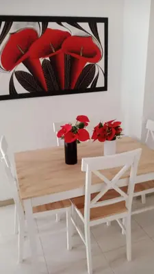 a dining room table with red flowers and a painting at Apartamento Playas de Marbella in Cartagena de Indias
