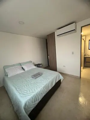 a bedroom with a large bed with white sheets at Apartment 5 minutes from the Airport, Sea and Center in Cartagena de Indias