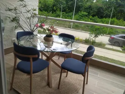 a glass table with blue chairs and a window at Apto de Ensueño en aguas cristalinas Baía Kristal in Cartagena de Indias
