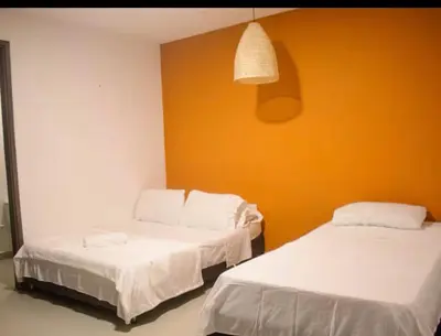 two beds in a room with an orange wall at Casa gimani Betts in Cartagena de Indias