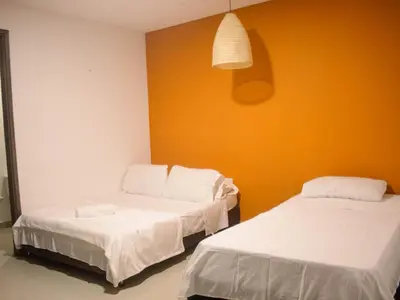two beds in a room with an orange wall at Casa gimani Betts in Cartagena de Indias