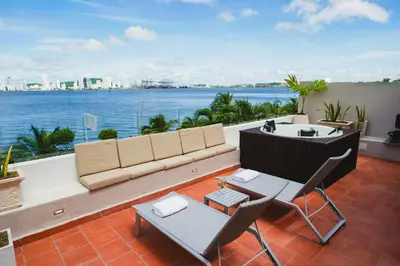 a couch and chairs on a balcony with a view of the water at Suite Premium con Terraza y Jacuzzi Privado in Cartagena de Indias