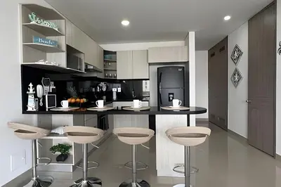 a kitchen with a bar with stools and a refrigerator at Hermoso Apto de 1 hab con Vista al Mar - Piso 16! in Cartagena de Indias