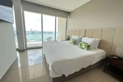 a bedroom with a bed with white sheets and green pillows at Lujoso Apto de 1 Habitación en Piso 17 -H2 Hyatt in Cartagena de Indias