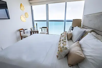 a bedroom with a large white bed with pillows at Espectacular Vista desde Piso 17 -Morros City 1701 in Cartagena de Indias