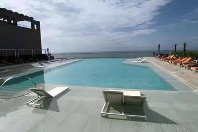 a swimming pool with lounge chairs and the ocean at 1702 Morros City - Espectacular Apto en Bocagrande in Cartagena de Indias