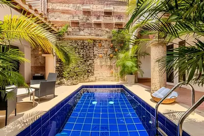 an indoor pool with blue tiles in a courtyard with palm trees at Casa Bóvedas - Paraíso de 5 habitaciones in Cartagena de Indias