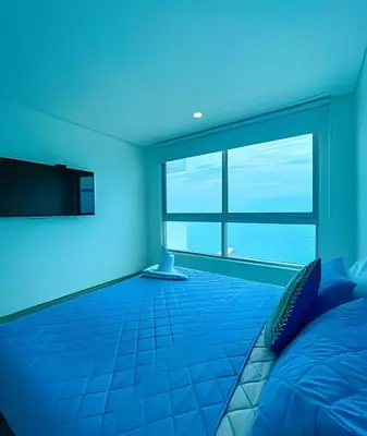 a blue room with a bed and a television at 1705 Palmetto Beach -17th Floor Palmetto Beach in Cartagena de Indias